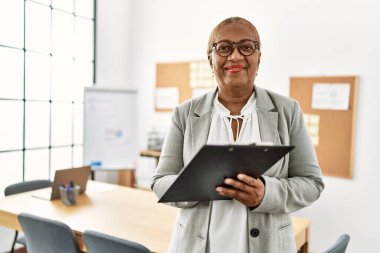 Kıdemli Afro-Amerikan kadın iş adamı. Ofisteki panoya yazı yazıyor.