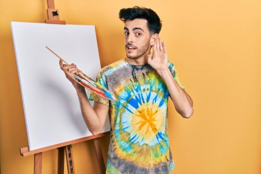 İspanyol asıllı genç adam paletle resim çiziyor boyacı sehpası sırıtarak dedikodu ya da dedikoduları dinliyor. Sağırlık kavramı. 