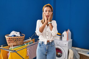Çamaşırhanedeki genç sarışın kadın korkmuş ve şok olmuş, şaşırmış ve hayrete düşmüş. 