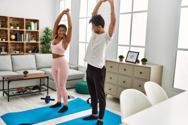 Genç Latin sporcu çift gülümseyerek evde mutlu bir antrenman yapıyor..