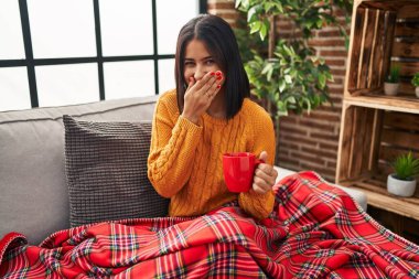 Genç İspanyol kadın kanepede oturup kahve içerken gülüyor ve utanıyor kıkırdıyor elleri, dedikoduları ve skandalları ağızlarıyla örtüyor. 