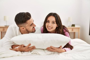 Genç İspanyol çift gülümseyerek mutlu bir şekilde yatakta yatıyor..