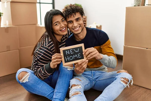 Young Latin Couple Holding New Home Blackboard Sitting Floor — Zdjęcie stockowe
