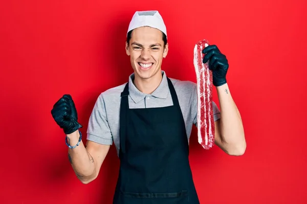 Young Hispanic Man Wearing Cook Apron Holding Meat Screaming Proud — Stock Photo, Image