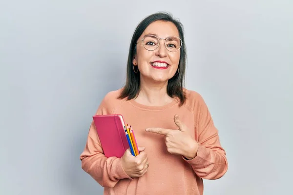 Hispanische Frau Mittleren Alters Mit Buch Und Buntstiften Lächelnd Glücklich — Stockfoto