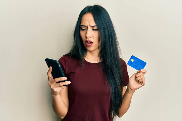 Ung Latinamerikansk Flicka Håller Smartphone Och Kreditkort Chock Ansikte Ser — Stockfoto