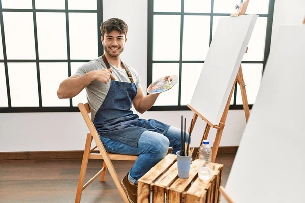 Młody Latynos Maluje Pracowni Sztuki Wskazując Palcem Siebie Uśmiechniętą Szczęśliwą — Zdjęcie stockowe