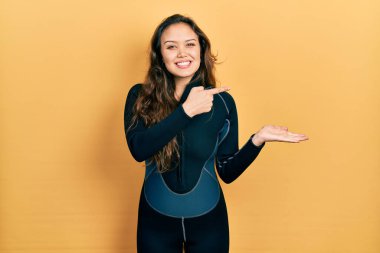 Dalgıç neoprene üniforması giyen genç İspanyol kız kameraya hayret ediyor ve gülümsüyor.. 