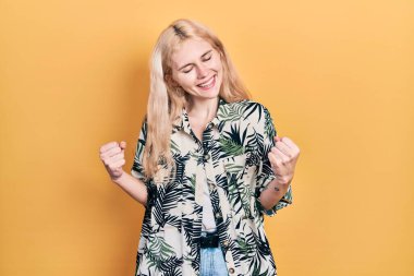 Sarışın, tropikal gömlek giyen güzel beyaz kadın. Başarı için heyecanlanıyor, kolları havada ve gözleri kapalı zaferi kutluyor. Kazanan konsept. 