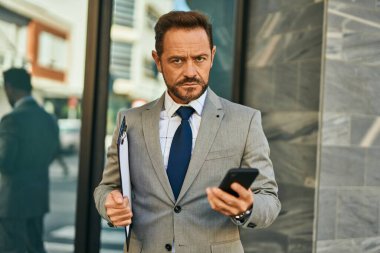 Şehirde akıllı telefon kullanan orta yaşlı bir işadamı..