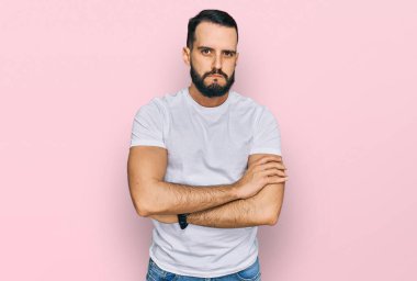 Sakallı, sıradan beyaz tişörtlü, kuşkucu ve gergin genç bir adam. Yüzünde çapraz kollu tasvip etmeyen bir ifade var. negatif kişi. 