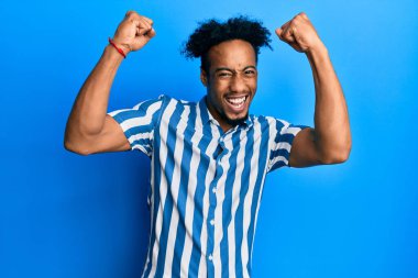 Sakallı, sıradan çizgili tişörtü olan genç Afro-Amerikalı adam kollarını kaldırıp, gözlerini açarak başarısını kutluyor ve şaşırıyor. Kazanan konsept. 