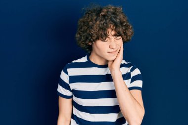 Diş ağrısı ya da diş hastalığından dolayı sıradan çizgili tişört giyen yakışıklı genç adam ağıza acı dolu bir ifadeyle dokunuyor. dişçi 