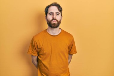 Sakallı, sıradan sarı tişörtlü beyaz bir adam kameraya bakıp havada öpücük yolluyor. Güzel ve seksi. aşk ifadesi. 