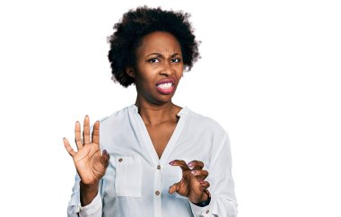 Afro-beyaz tişörtlü Afro-Amerikalı kadın tiksindirici ve tiksindirici bir yüz ifadesi takınıyor. Eller havada. 