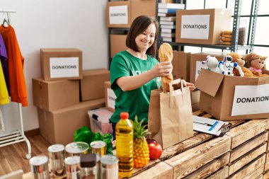 Down sendromlu esmer kadın bağış standında bağışlanan yiyecekleri kese kağıdına koydu.
