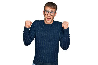 Gündelik kıyafetler giyen ve gözlük takan genç sarışın adam başarı için şaşırmış ve hayrete düşmüştü. Kolları açık ve gözleri açıktı. Kazanan konsept. 