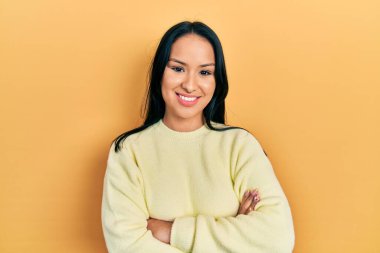 Burnuna piercing takan, sıradan sarı süveter giyen, kollarını kavuşturup kameraya bakan güzel İspanyol kadın. pozitif kişi. 