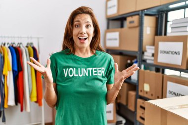 Bağışlarda gönüllü tişört giyen orta yaşlı İspanyol kadın zaferi mutlu bir gülümsemeyle ve ellerini kaldırarak kutluyor. 