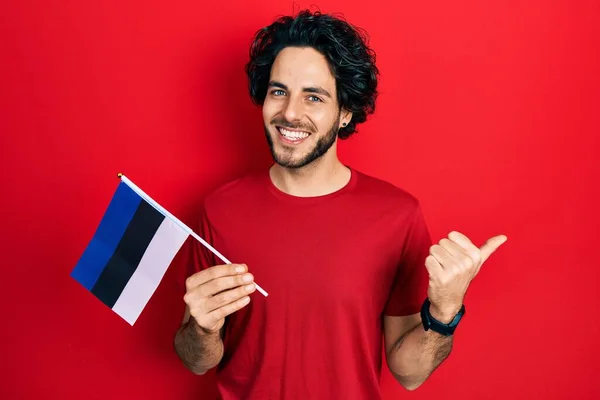 ハンサムHispanic男保持Estonia Flag指して親指へザサイド笑顔幸せとともにオープン口 — ストック写真
