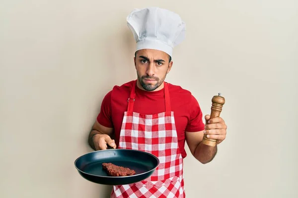 Young Hispanic Man Wearing Professional Cook Uniform Hat Cooking Beef — Stockfoto