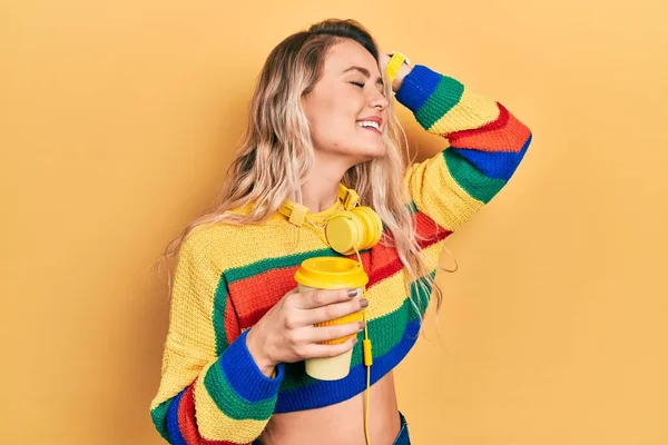 Piękna Młoda Blondynka Pije Filiżankę Kawy Nosząc Słuchawki Uśmiechając Się — Zdjęcie stockowe
