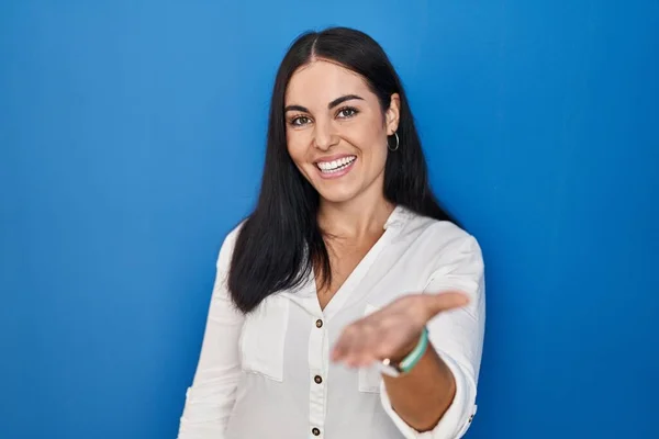 Jonge Spaanse Vrouw Staan Blauwe Achtergrond Glimlachend Vrolijk Aanbieden Palm — Stockfoto