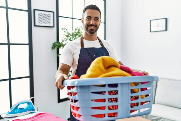 Joven Hombre Hispano Sonriendo Confiado Sosteniendo Canasta Con Ropa Casa — Foto de Stock