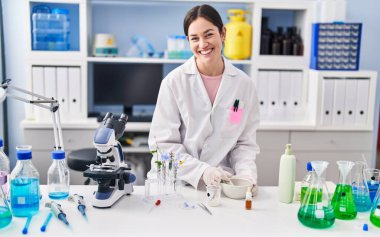 Laboratuvarda çalışan bilim adamı üniforması giyen genç bir kadın.