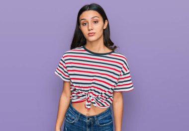 Günlük kıyafetler giyen genç İspanyol kız yüzünde ciddi bir ifadeyle rahatlamış. Basit ve doğal bir şekilde kameraya bakıyorsun.. 