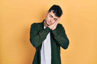 Gündelik kıyafetler giyen genç İspanyol adam uyur. Yorgun düşler kurar, ellerle poz verir, gözleri kapalı gülümserdi.. 