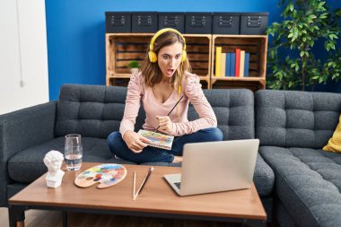 Genç, güzel bir kadın internette resim yapmaya çalışıyor. Korkmuş ve ağzı açık kalmış, imansız bir yüz ifadesi var. 