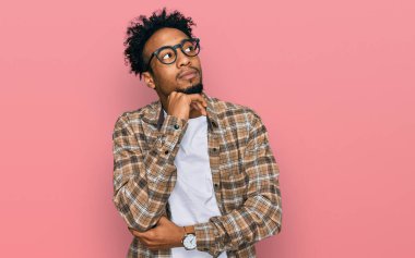 Sakallı, sıradan giyinmiş, çenesi üzerinde gözlüklü soru soran, düşünceli, genç Afro-Amerikan adam. Gülümseyen ve düşünceli bir yüz. şüphe kavramı. 