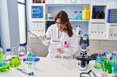 Laboratuvarda Louise 'i kullanarak bilim adamı üniforması giyen genç Latin bir kadın.