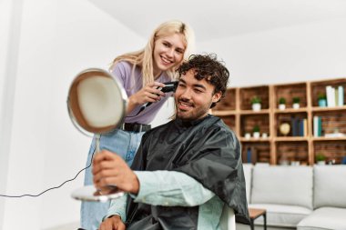 Genç bir kadın evdeki erkek arkadaşına saç kesiyor..