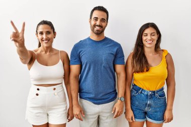 Tecrit edilmiş arka planda duran bir grup İspanyol genç iki numarayı gösterip işaret ederken kendinden emin ve mutlu bir şekilde gülümsüyor.. 