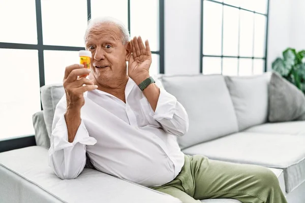 Uomo Anziano Che Tiene Pillole Sorridendo Con Mano Sull Orecchio — Foto Stock