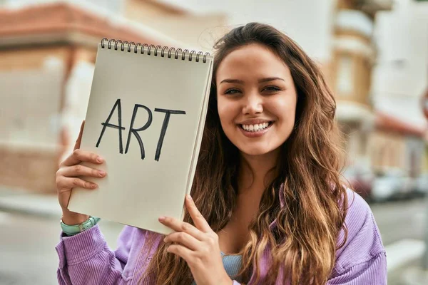 Joven Estudiante Arte Hispana Sonriendo Feliz Sosteniendo Cuaderno Ciudad —  Fotos de Stock