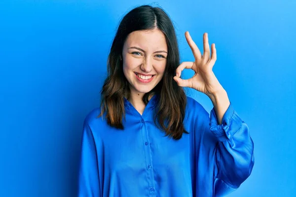 年轻的黑发女人穿着休闲的蓝色衬衫 面带微笑 手指手画脚地签了名 成功表达 — 图库照片