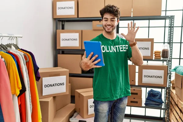 Jonge Spaanse Man Vrijwilligersuniform Met Videogesprek Een Liefdadigheidscentrum — Stockfoto