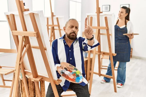 アートスタジオのシニアアーティスト男は指を上げて怒りの表情で指摘し ジェスチャーを見せません — ストック写真