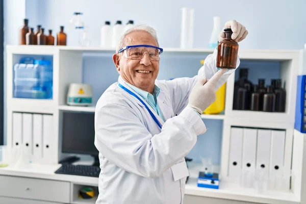 研究室で科学者の制服を着た先輩が瓶を持って — ストック写真