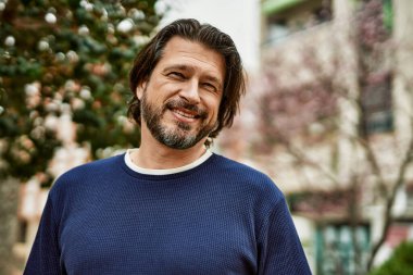 Kasabada gülümseyen orta yaşlı yakışıklı bir adam.