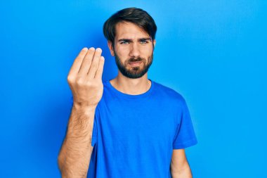 Gündelik kıyafetler giyen genç İspanyol adam İtalyan jesti yapıyor. El ve parmaklarıyla kendinden emin ifade ediyor. 