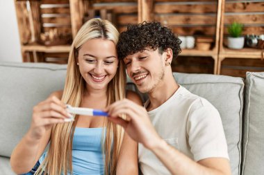 Mutlu gülümseyen genç çift evde hamile görünüyor..