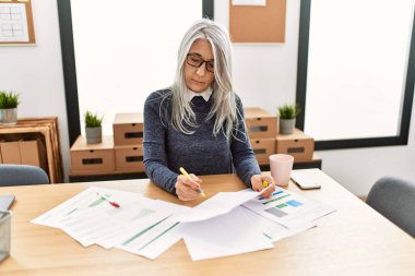Ofiste çalışırken gülümseyen beyaz saçlı iş kadını.