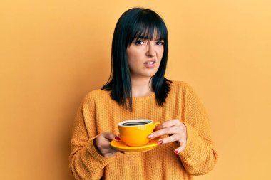 Genç İspanyol kadının elinde kafasız ve kafası karışık bir kahve var. şüphe kavramı. 