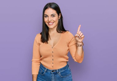 Gündelik kıyafetler giyen genç İspanyol kadın başarılı bir fikri işaret ediyor. Heyecanlı ve mutlu. Bir numara.. 