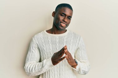 Genç, Afro-Amerikan bir adam günlük giysiler içinde ellerini birleştirip gülümseyerek rahat ve neşeli bir şekilde gülümsedi. Başarı ve iyimserlik 