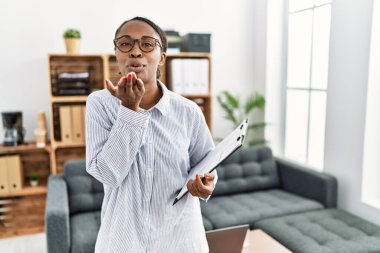 Psikoloji kliniğinde çalışan Afrikalı bir kadın kameraya bakıp havada öpüşürken güzel ve seksi görünüyor. aşk ifadesi. 